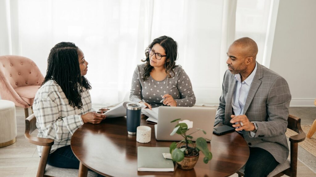 Trois personnes en discussion autour d'une table, examinant des documents dans un cadre professionnel sur le RGPD.